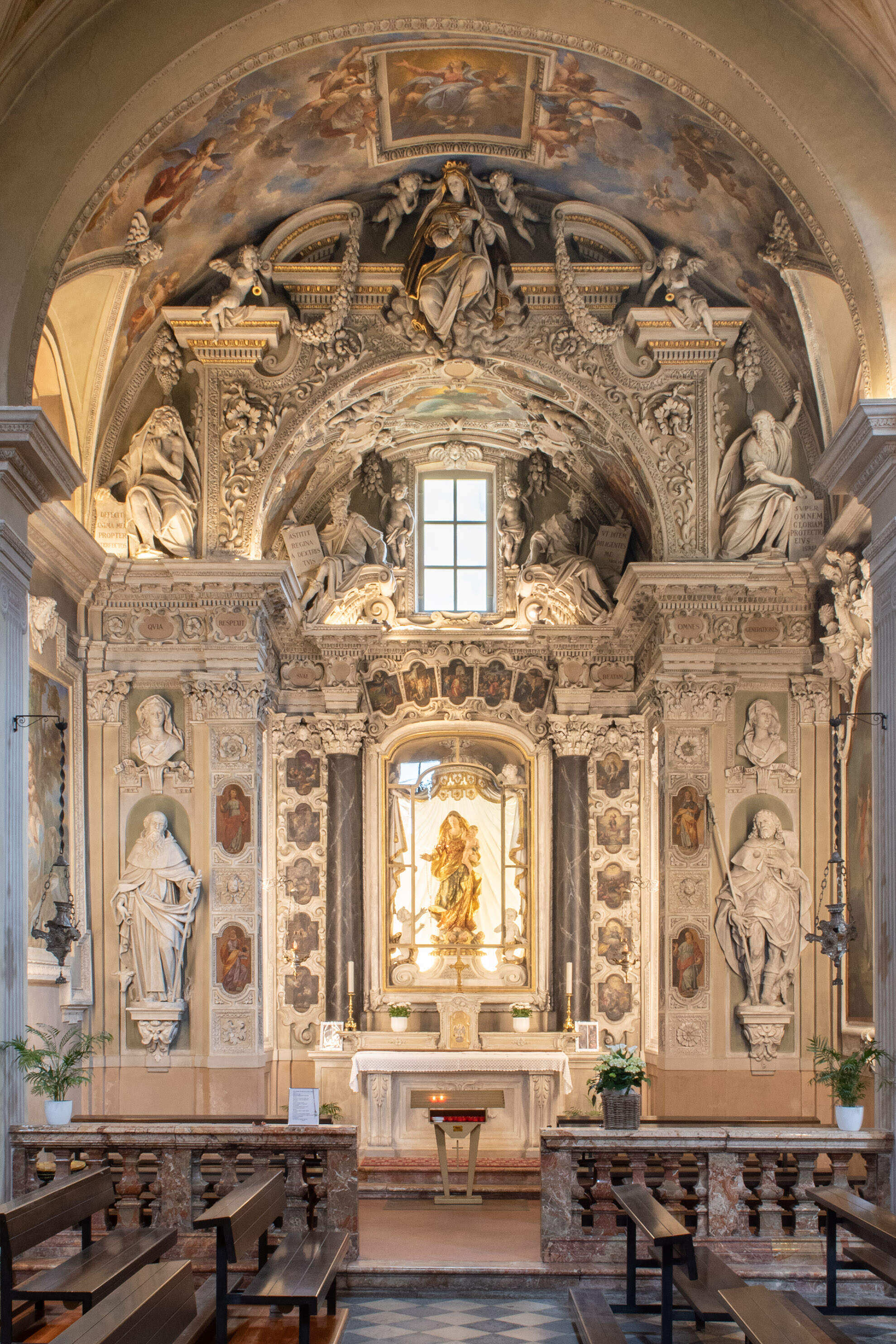 An interior of a Baroque-style chapel with an ornate altar, adorned with sculptures, frescoes, and intricate stucco work.