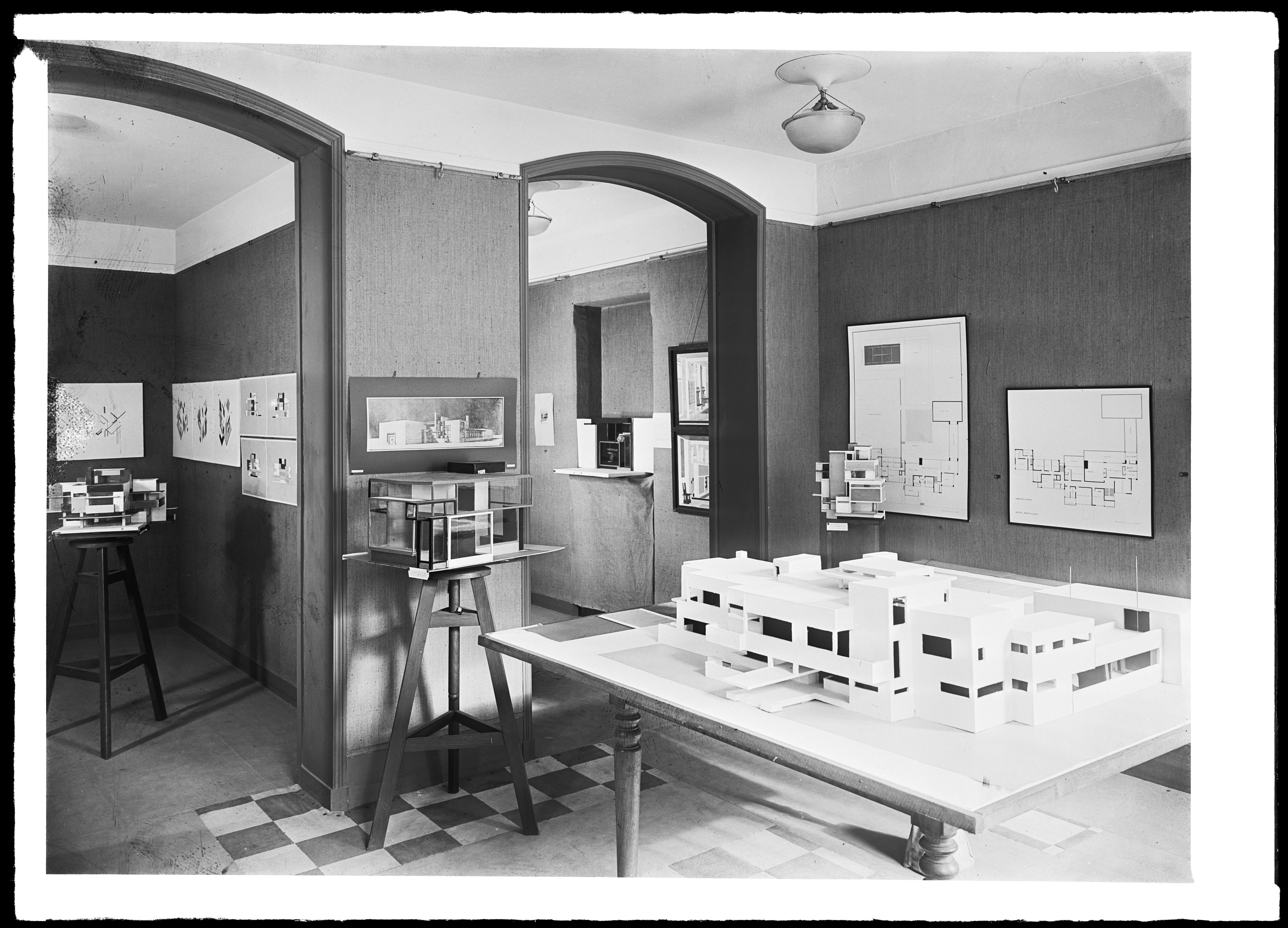 Black and white photograph of the exhibition space at Galerie l’Effort Moderne in Paris. The space features several maquettes and artworks displayed on the walls.
