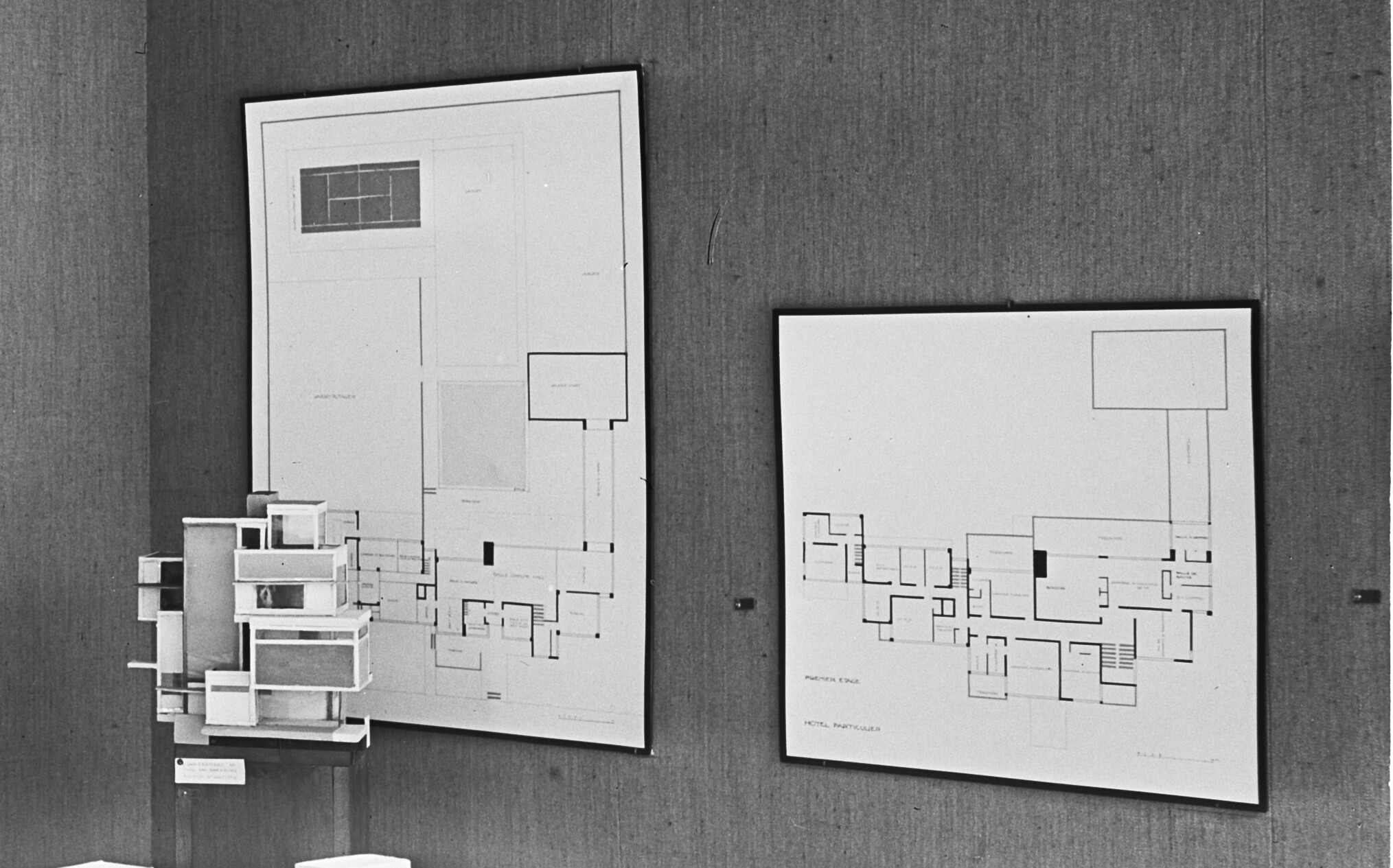 Detail of the black and white photograph of the De Stijl exhibition at Galerie l’Effort Moderne, zooming in on the ground- and first-floor plans of Hôtel Particulier on the wall; in the front is the maquette of Maison d’Artiste.